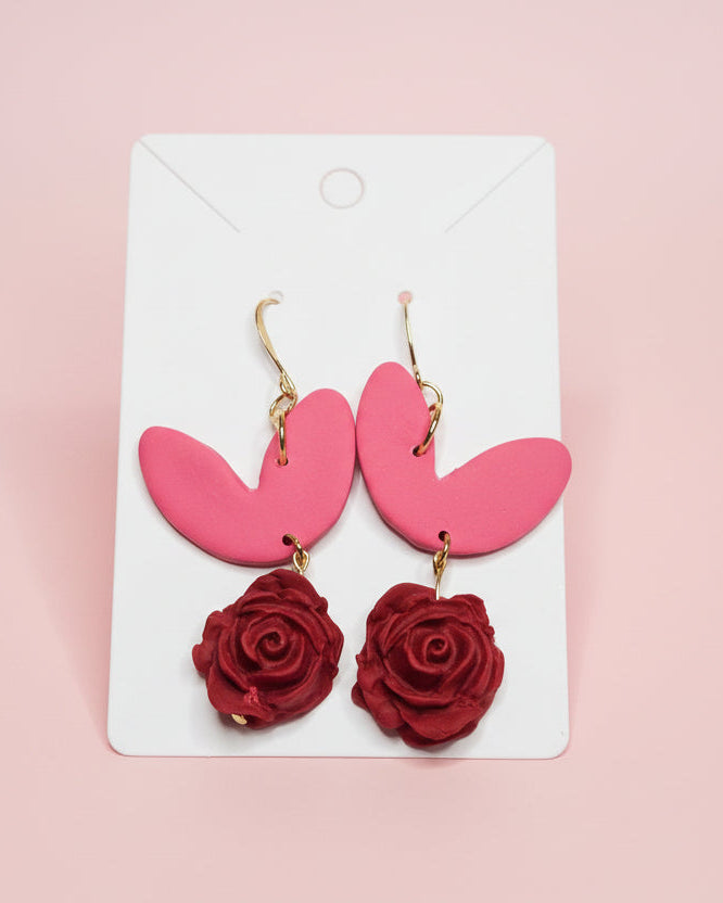 Pink earrings with red rose details on a pink background