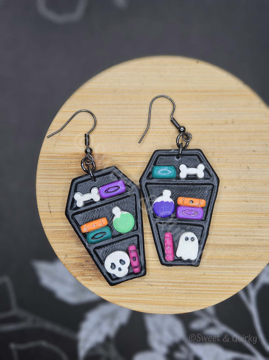 Pair of Halloween-themed earrings on a wooden surface with a dark background.