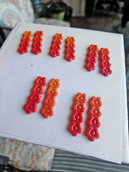 Red and orange decorative earrings on a white surface with a blurred background
