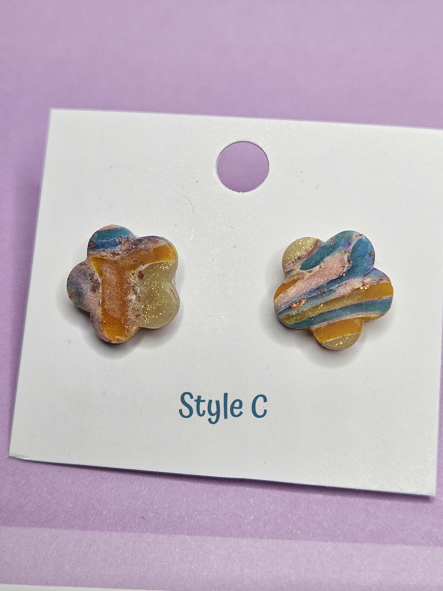 Colorful flower-shaped earrings on a white card with 'Style C' text, against a purple background
