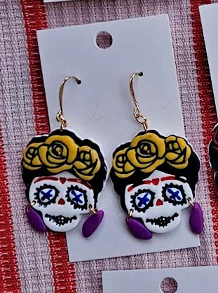 Day of the Dead-themed earrings on a card with a striped background