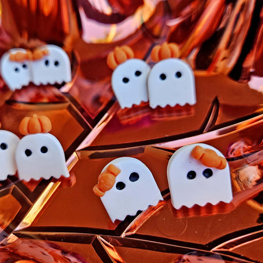 Halloween-themed ghost and pumpkin decorations on a reflective surface.