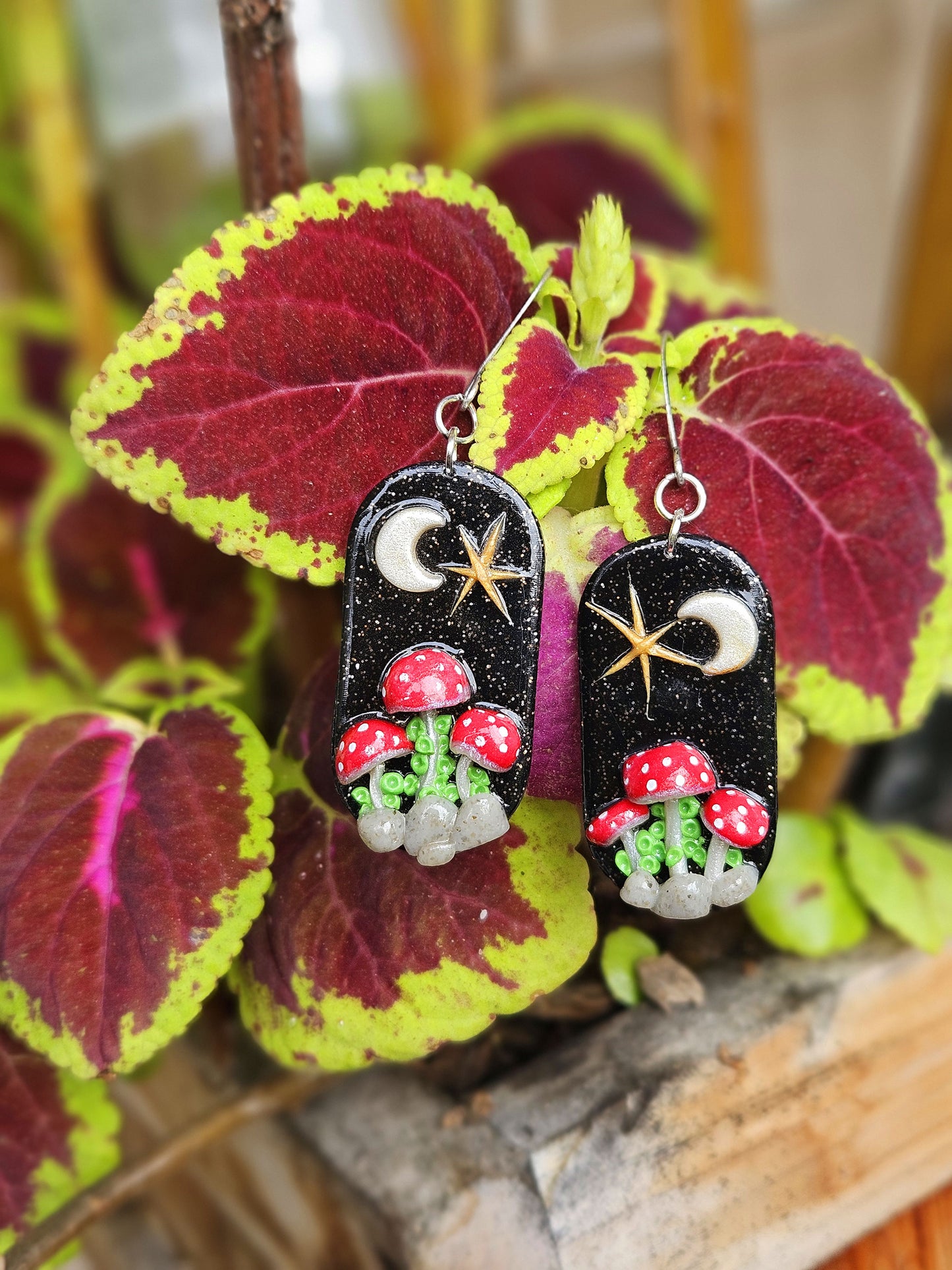 Pair of earrings with mushroom design on a leafy background