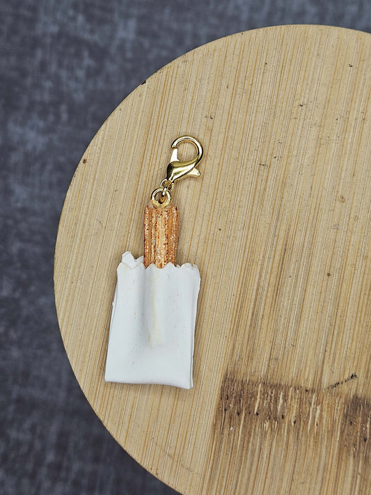 Keychain resembling a bag of churros on a wooden surface with a dark background