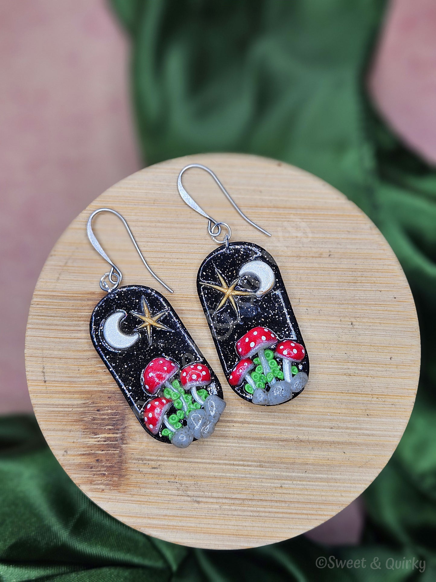 Pair of earrings with mushroom design on a wooden surface