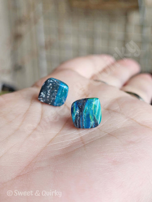 Blue marbled earrings held on a hand.