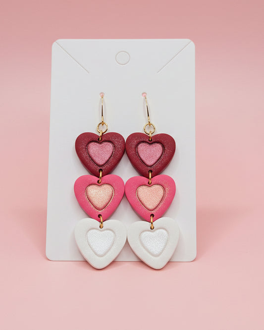 Heart-shaped earrings on a white card with a gray background