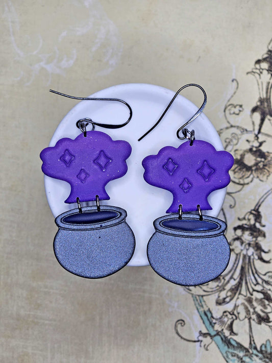 Purple and gray earrings on a white stand with a decorative background