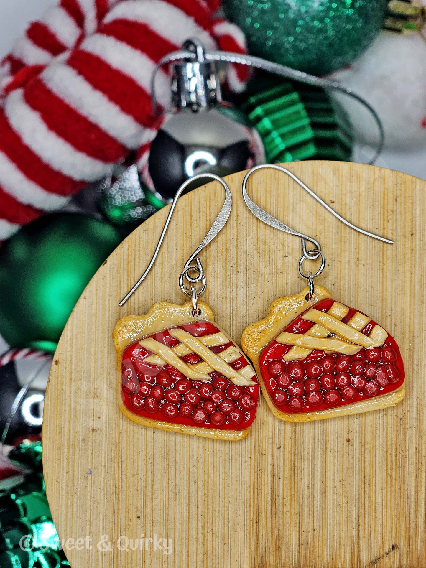 Pie-shaped earrings on a wooden board with Christmas ornaments in the background