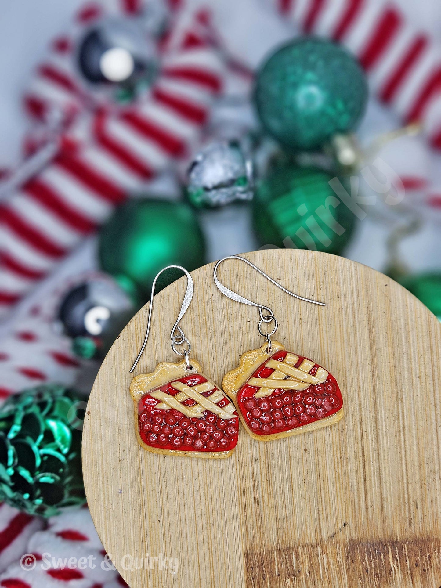 Pie-shaped earrings on a wooden board with Christmas decorations in the background