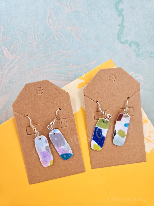 Colorful earrings on brown earring cards with a light blue and yellow background