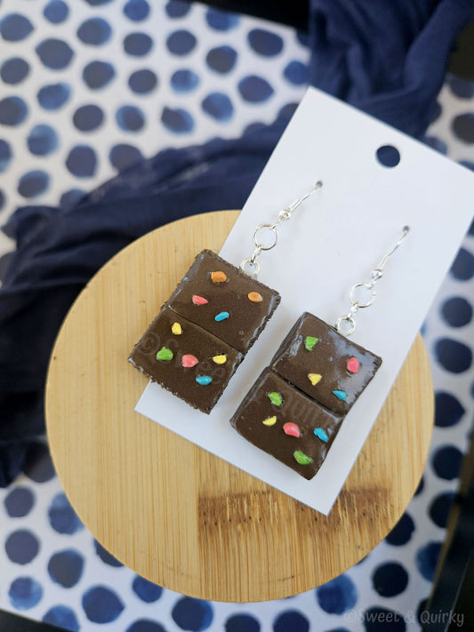 Brownie bar-shaped earrings on a wooden stand with a polka dot background