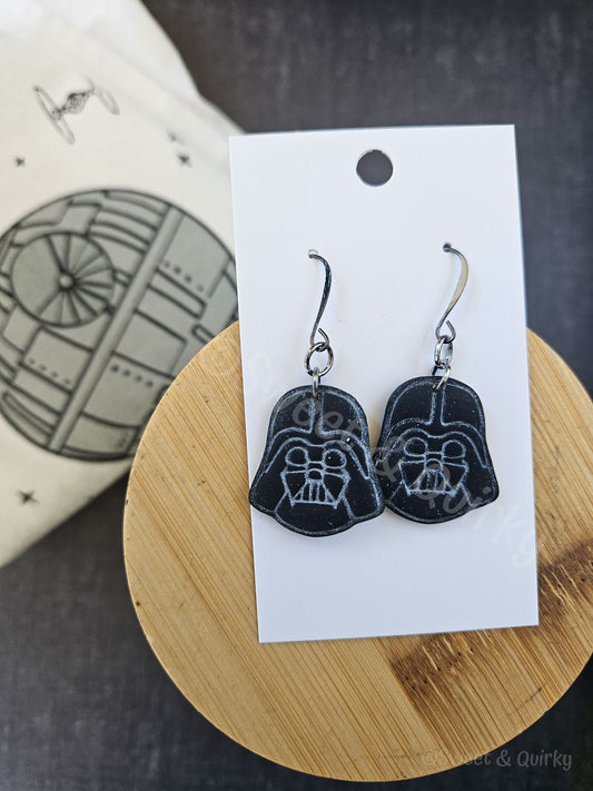 Darth Vader earrings on a white card with a wooden stand and blurred background