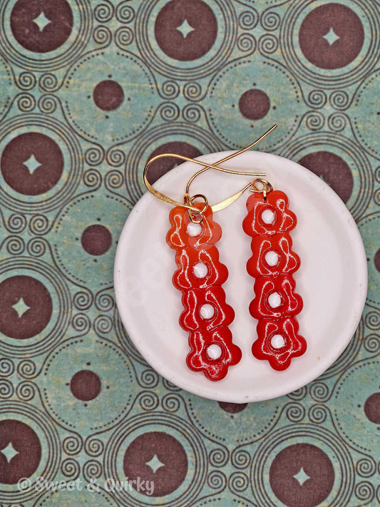 Red floral earrings on a white dish with a patterned background