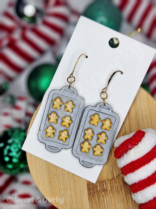 Gray gingerbread mold earrings on a white card with a Christmas-themed background.