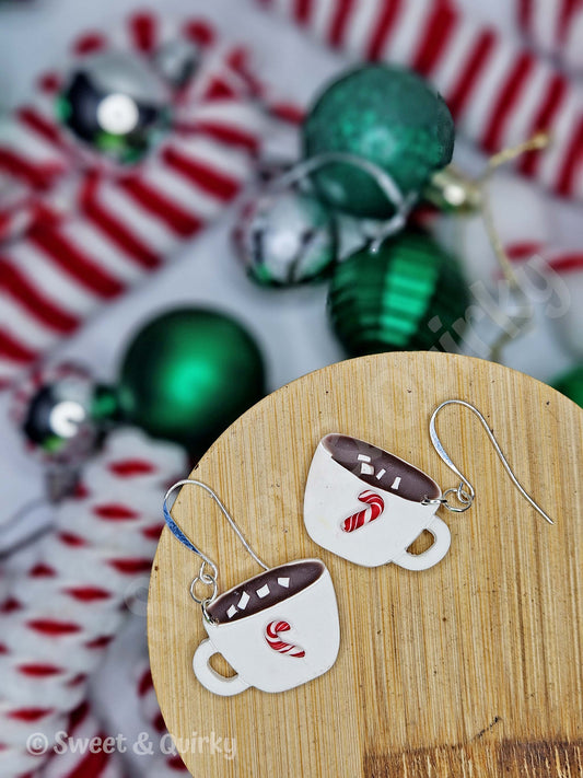 Cup-shaped earrings on a wooden stand with Christmas ornaments in the background
