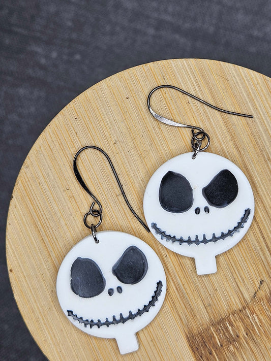 Skull-shaped earrings on a wooden surface with a dark background