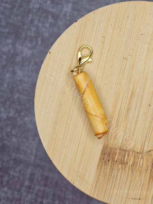 Filipino lumpia charm on a wooden surface with a blurred gray background
