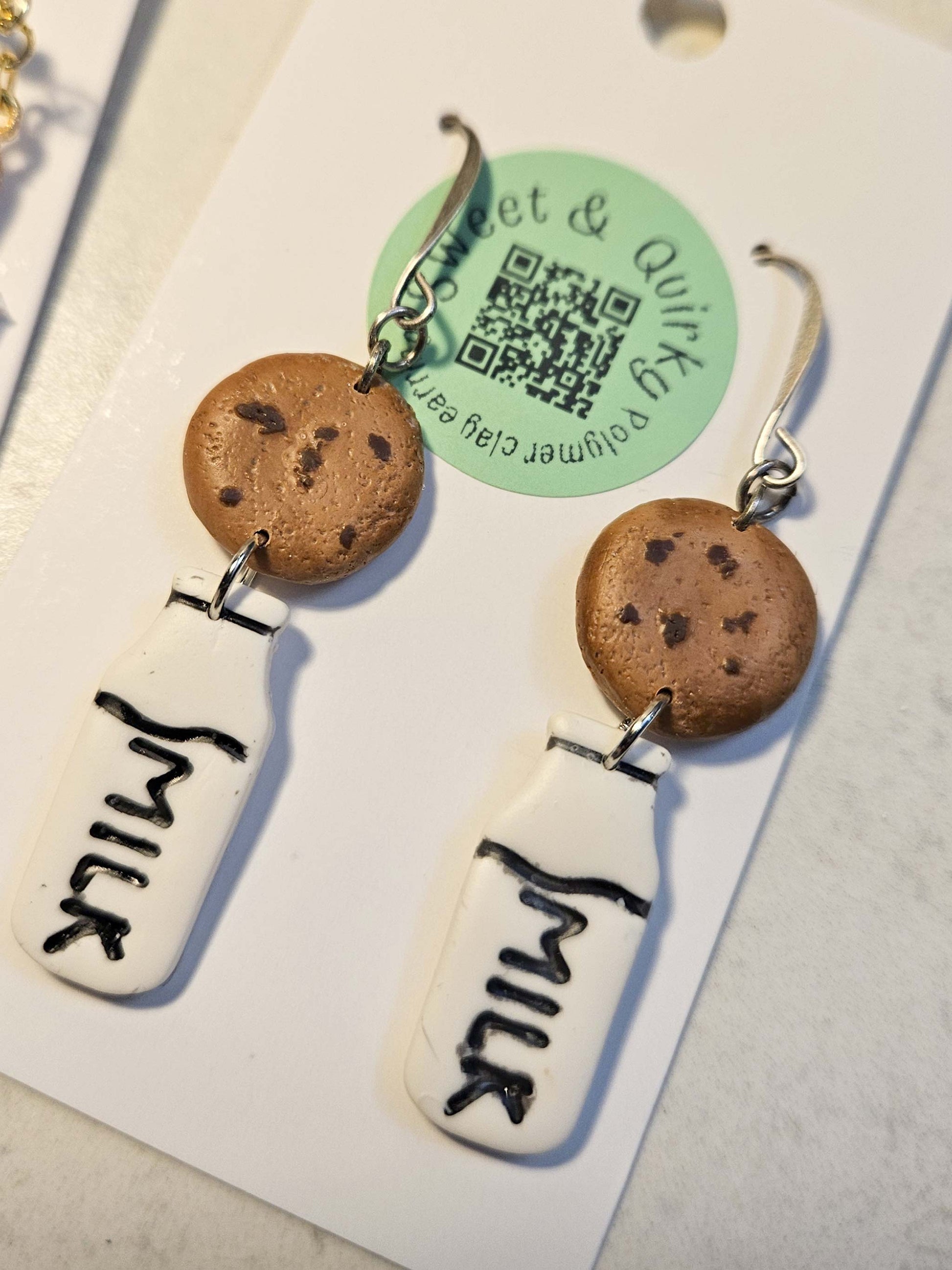 Cookie and milk earrings with a 'milk' label on a card.
