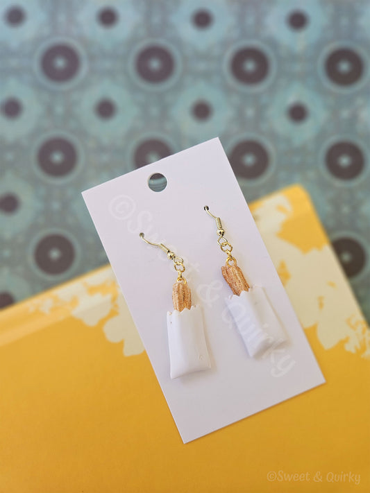Pair of earrings on a white card with a patterned background