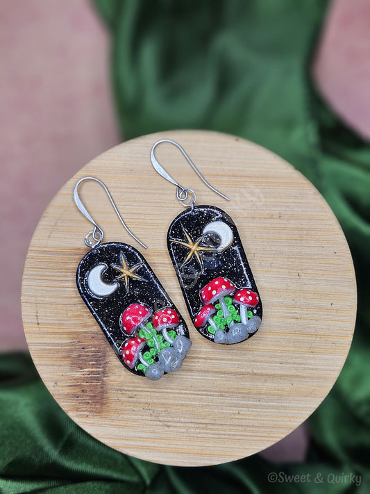 Pair of earrings with mushroom design on a wooden surface
