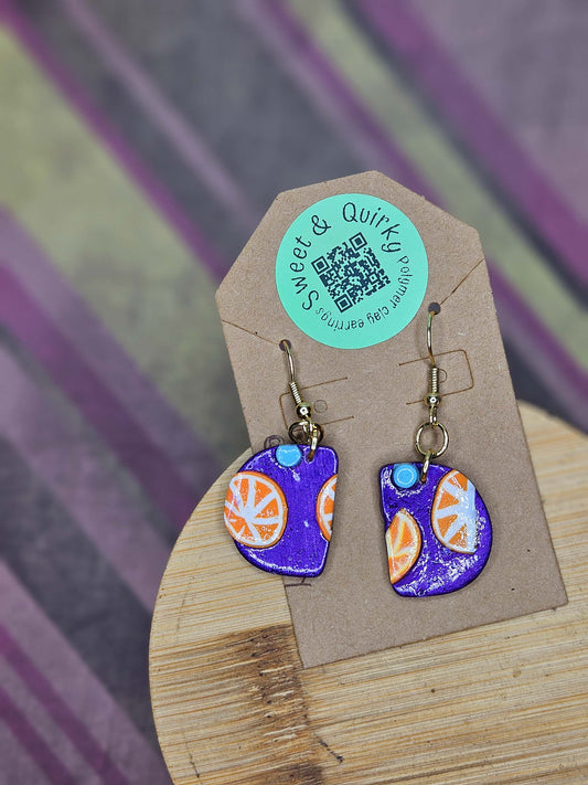 Colorful earrings on a wooden stand with a 'Sweet & Quirky' label.