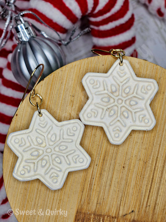 Snowflake earrings on a wooden board with a blurred background