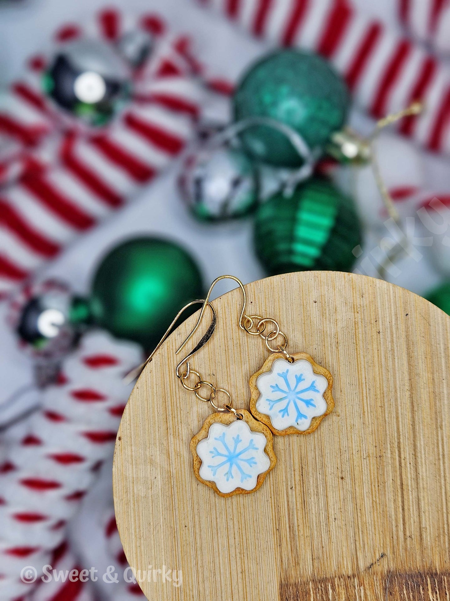 Snowflake-shaped earrings on a wooden stand with Christmas ornaments in the background
