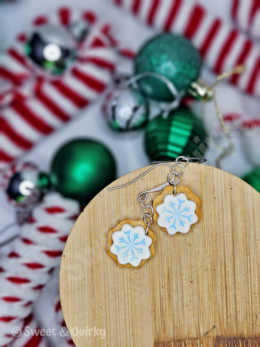 Snowflake earrings on a wooden display with Christmas ornaments in the background
