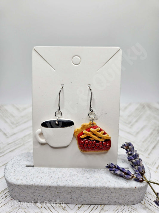 Earrings shaped like a coffee cup and pie on a display card with a lavender flower.